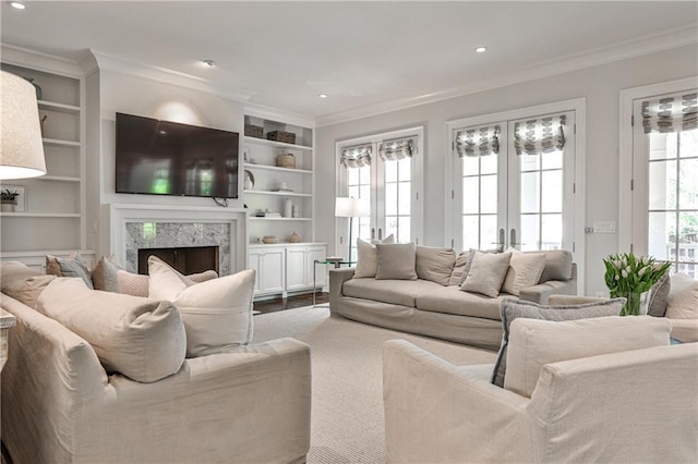 living room with crown molding, a fireplace, recessed lighting, french doors, and built in shelves