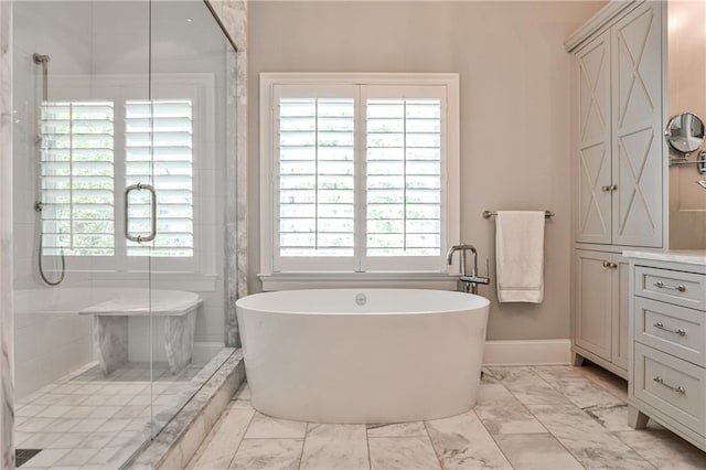 full bath featuring a wealth of natural light, a freestanding tub, marble finish floor, and a stall shower