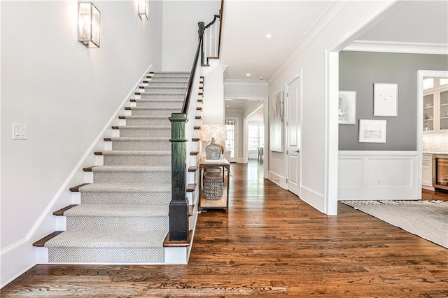 foyer featuring dark wood-style floors, wine cooler, ornamental molding, and stairs