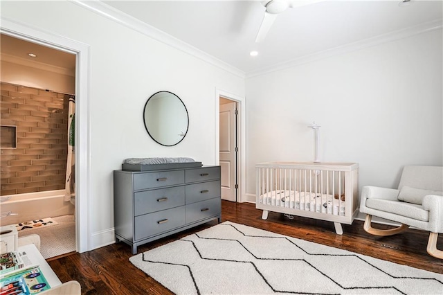 bedroom featuring dark wood-style floors, baseboards, ornamental molding, and a nursery area