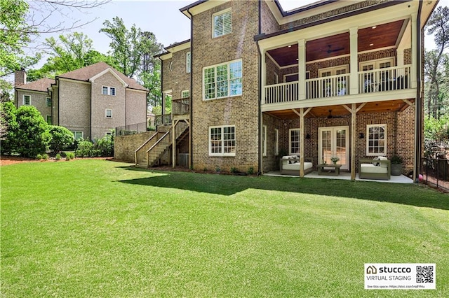 back of house with a yard, a ceiling fan, stairway, a patio, and brick siding