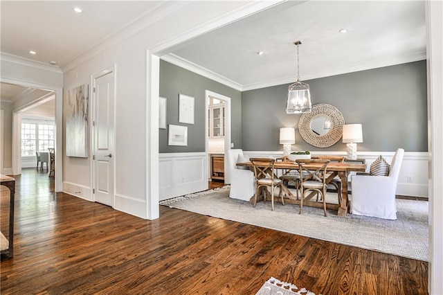 dining space featuring a notable chandelier, ornamental molding, a wainscoted wall, and wood finished floors