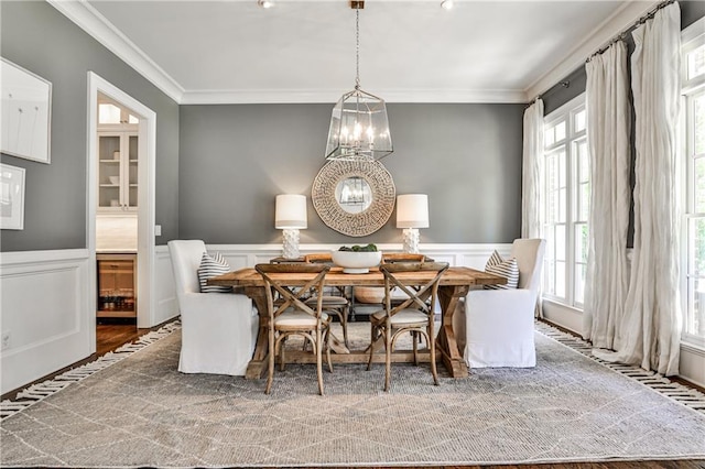 dining area with a chandelier, a decorative wall, and ornamental molding