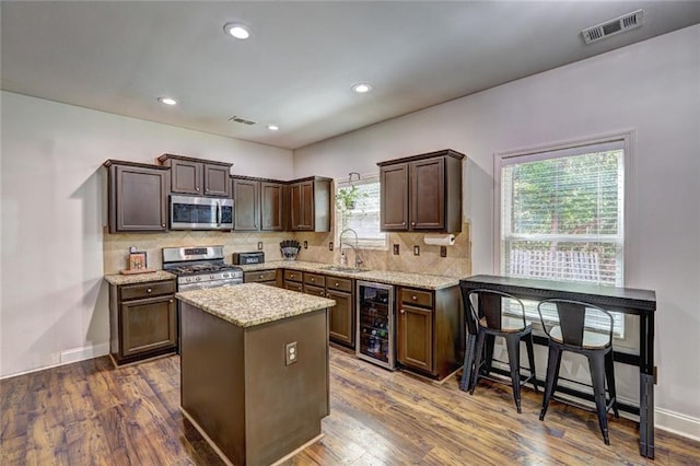 kitchen with a center island, sink, stainless steel appliances, wine cooler, and dark hardwood / wood-style floors