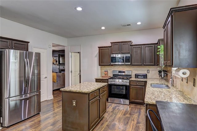 kitchen featuring sink, a center island, stainless steel appliances, dark hardwood / wood-style floors, and backsplash