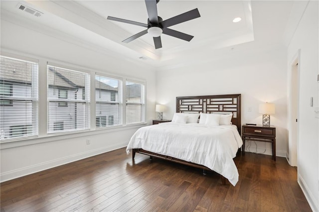 bedroom featuring ceiling fan, dark hardwood / wood-style flooring, and a raised ceiling