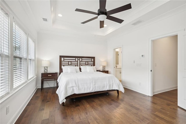 bedroom with crown molding, dark wood-type flooring, a raised ceiling, and ceiling fan