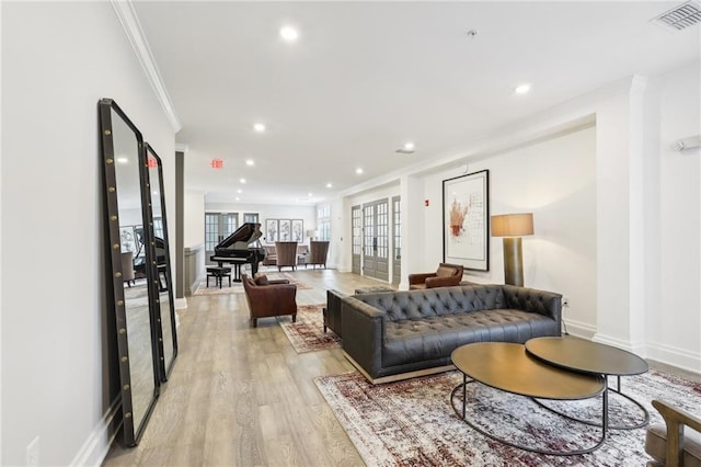 living room with crown molding, light hardwood / wood-style floors, and french doors