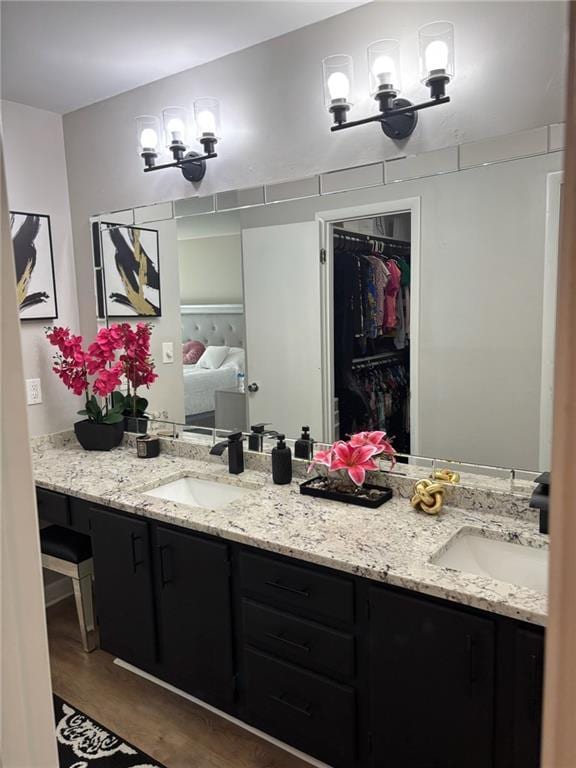 bathroom featuring double vanity, a sink, a walk in closet, and an inviting chandelier