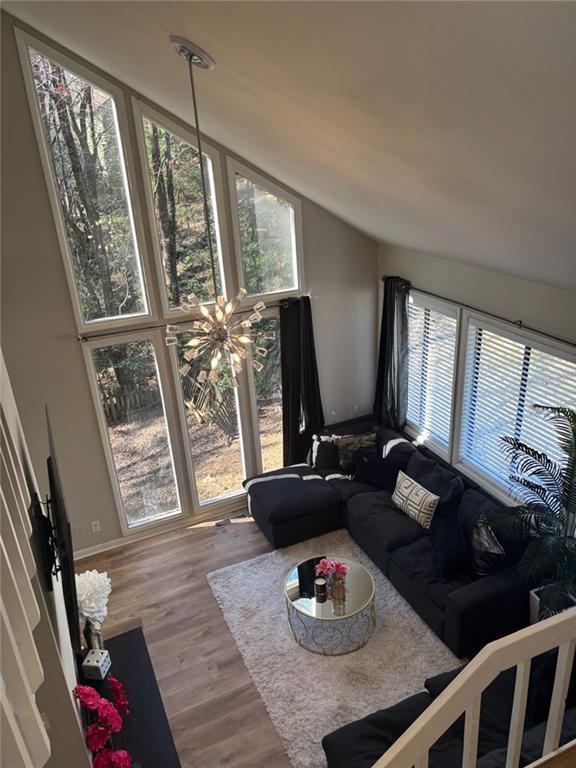 living room with vaulted ceiling, wood finished floors, and a notable chandelier