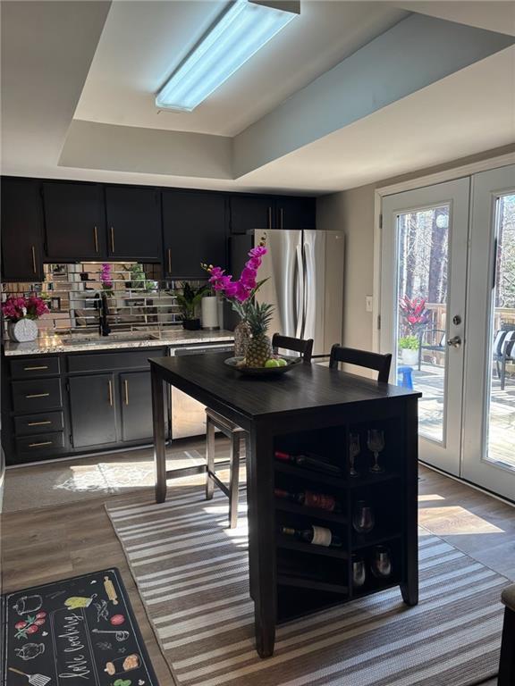 kitchen featuring freestanding refrigerator, light countertops, dark cabinetry, french doors, and a sink