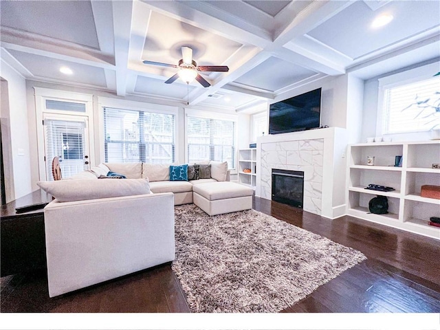 living room featuring beam ceiling, a tile fireplace, dark wood-type flooring, and coffered ceiling