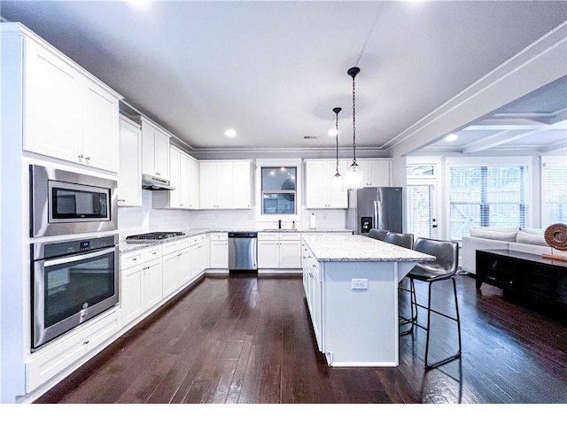 kitchen featuring appliances with stainless steel finishes, a kitchen breakfast bar, decorative light fixtures, white cabinets, and a center island