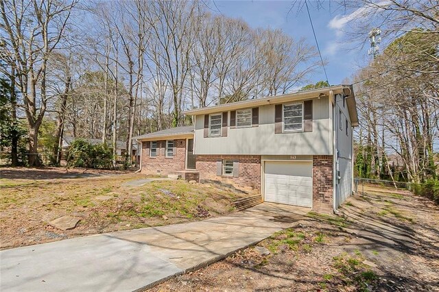 tri-level home with brick siding, concrete driveway, and an attached garage