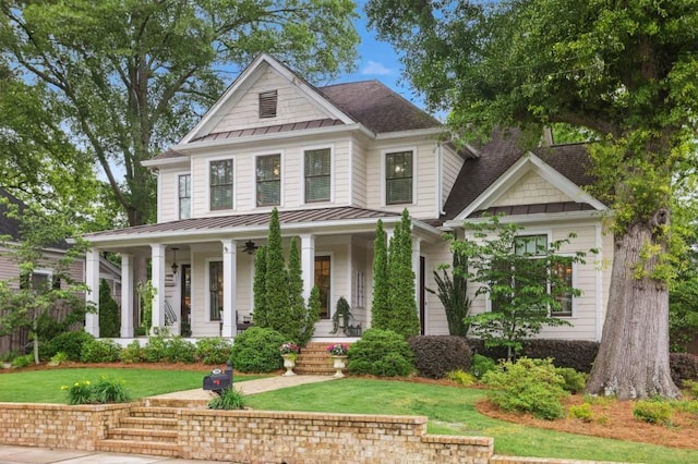 view of front of house with a standing seam roof, covered porch, a front yard, roof with shingles, and metal roof