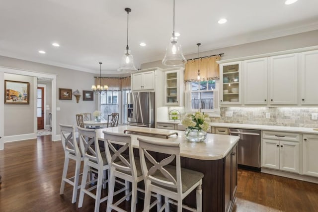 kitchen with appliances with stainless steel finishes, a kitchen island, backsplash, a breakfast bar, and ornamental molding