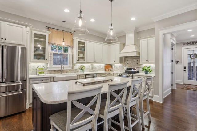 kitchen featuring stainless steel appliances, custom range hood, a sink, a kitchen bar, and recessed lighting