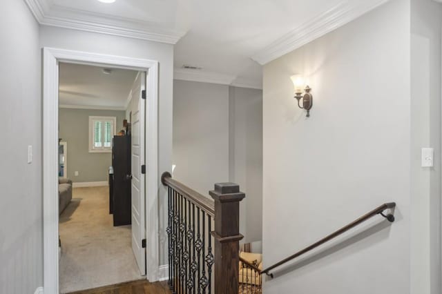 hall with an upstairs landing, crown molding, baseboards, and carpet floors