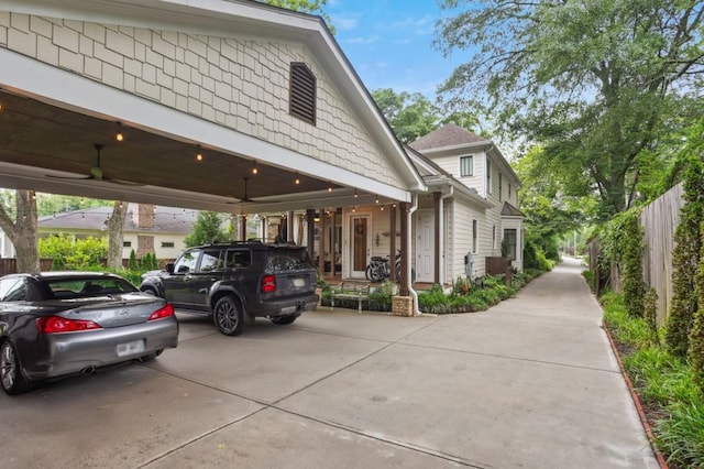view of property exterior with a carport, ceiling fan, and fence