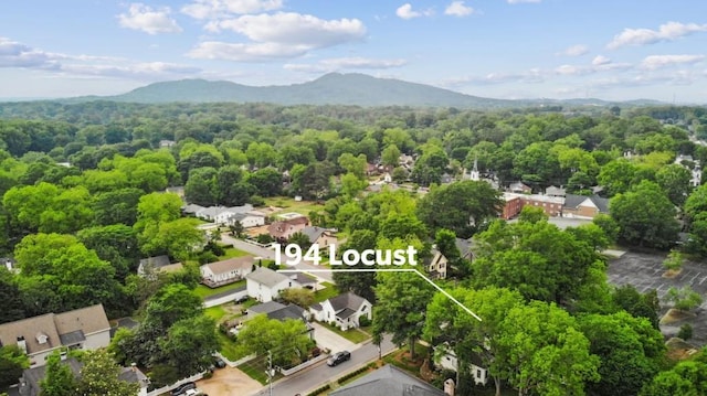 aerial view of residential area featuring a mountainous background and a heavily wooded area