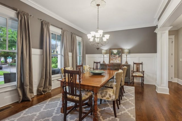 dining area with crown molding, wood finished floors, healthy amount of natural light, decorative columns, and a decorative wall