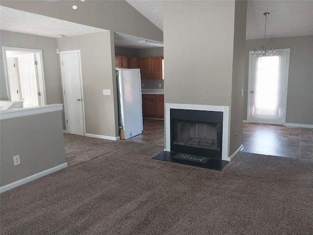 unfurnished living room featuring dark carpet, a chandelier, and vaulted ceiling