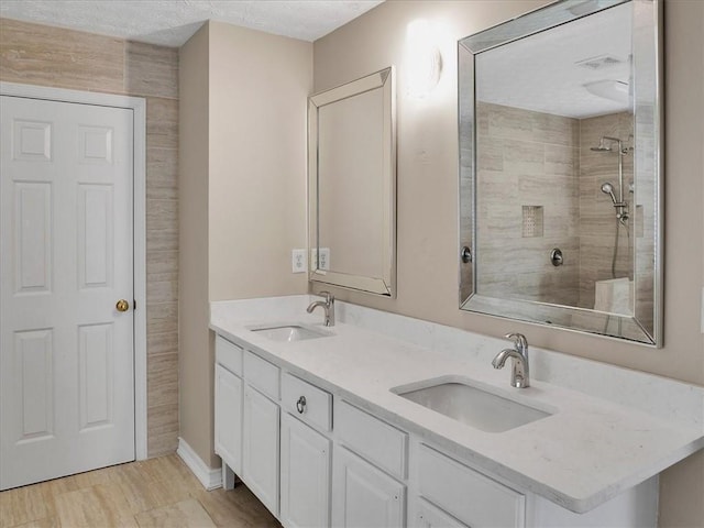 3725 Crescent Walk Ln, Suwanee, GA 30024 - full bathroom featuring double vanity, a textured ceiling, wood finished floors, and a tile shower