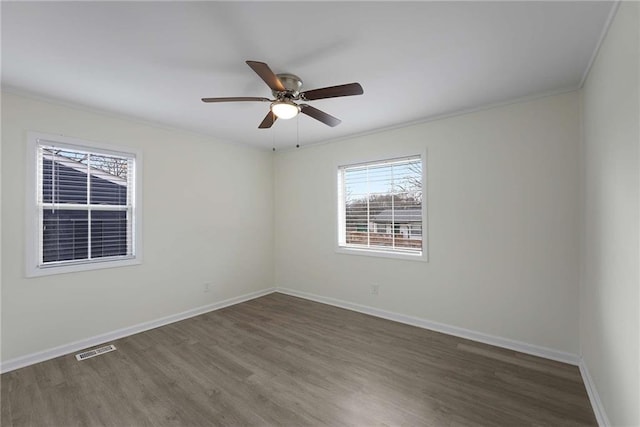 empty room featuring visible vents, wood finished floors, crown molding, baseboards, and ceiling fan