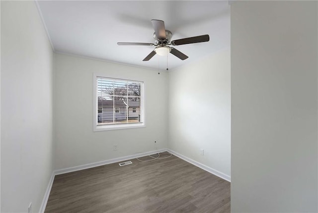 spare room with baseboards, dark wood-type flooring, ornamental molding, and a ceiling fan