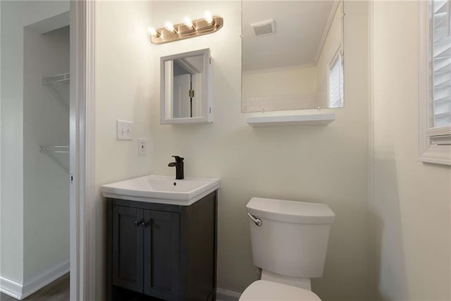 bathroom with visible vents, baseboards, toilet, and vanity