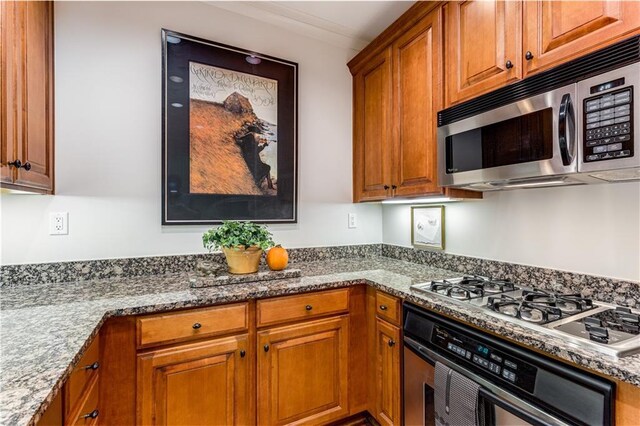 kitchen featuring stainless steel appliances, brown cabinetry, and stone countertops