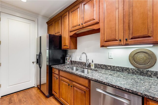 kitchen with brown cabinetry, fridge with ice dispenser, a sink, and stainless steel dishwasher