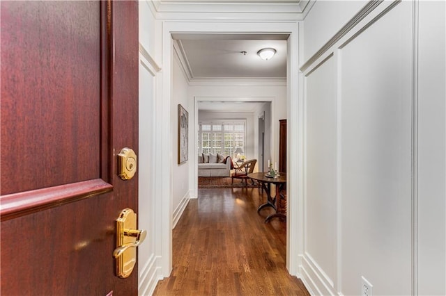 corridor with ornamental molding and wood finished floors