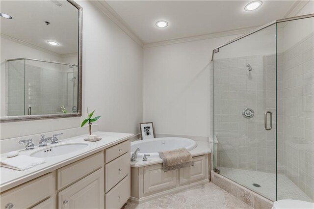 bathroom with ornamental molding, a stall shower, a garden tub, and vanity