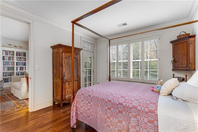 bedroom with ornamental molding, visible vents, baseboards, and wood finished floors