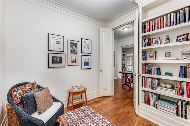 living area with ornamental molding, wood finished floors, and baseboards