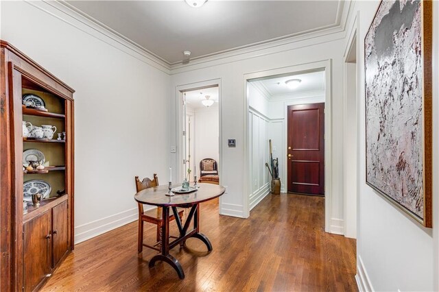 corridor featuring baseboards, wood finished floors, and crown molding