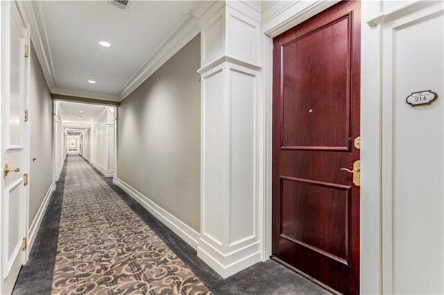 corridor with recessed lighting, dark colored carpet, visible vents, ornamental molding, and baseboards