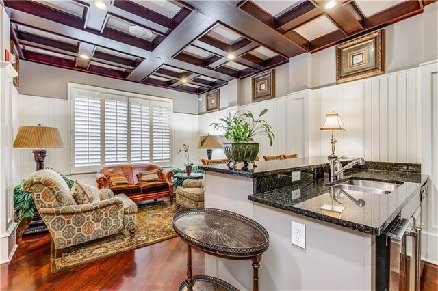 kitchen with coffered ceiling, dark stone countertops, dark wood finished floors, and a sink