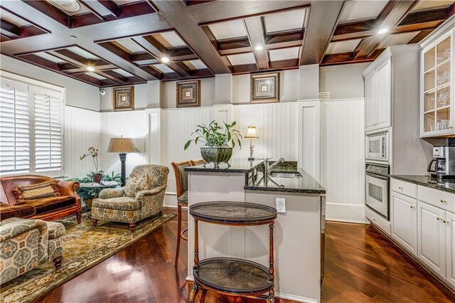 sitting room featuring dark wood-type flooring, coffered ceiling, and beamed ceiling