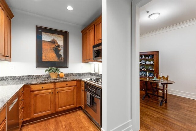 kitchen featuring light wood-type flooring, brown cabinetry, stainless steel appliances, and crown molding