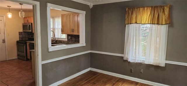 empty room featuring sink, crown molding, and tile patterned floors