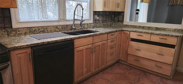 kitchen featuring sink, dark tile patterned floors, light stone counters, and dishwasher