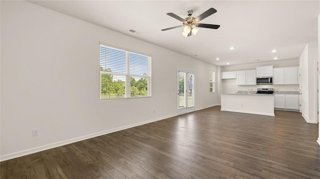 unfurnished living room with ceiling fan and dark hardwood / wood-style flooring