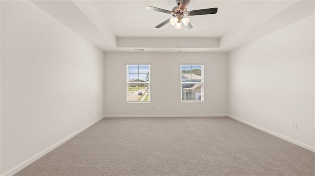 carpeted empty room with ceiling fan and a tray ceiling