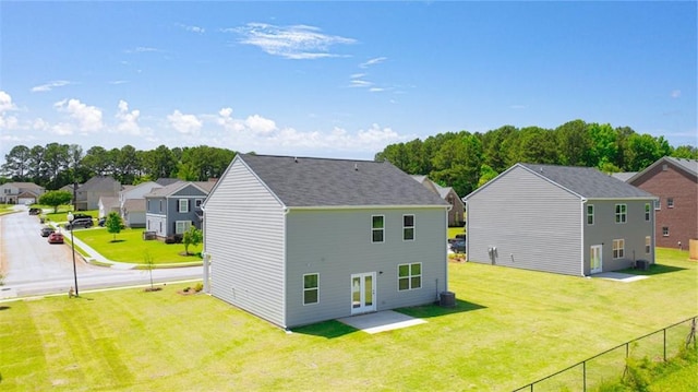 rear view of property featuring central AC unit and a lawn