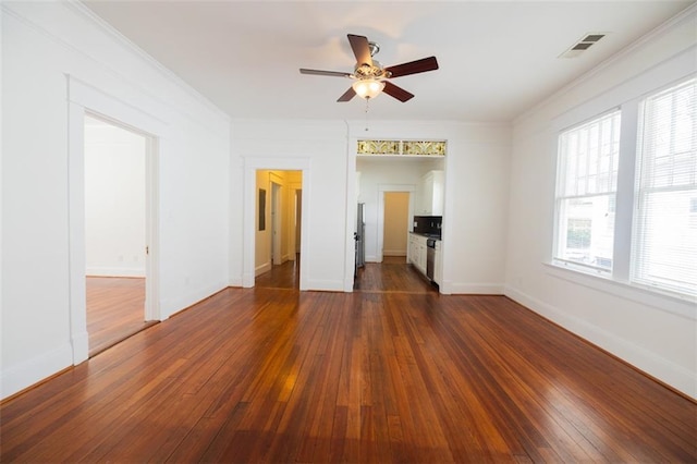 spare room featuring dark wood finished floors, ornamental molding, visible vents, and ceiling fan