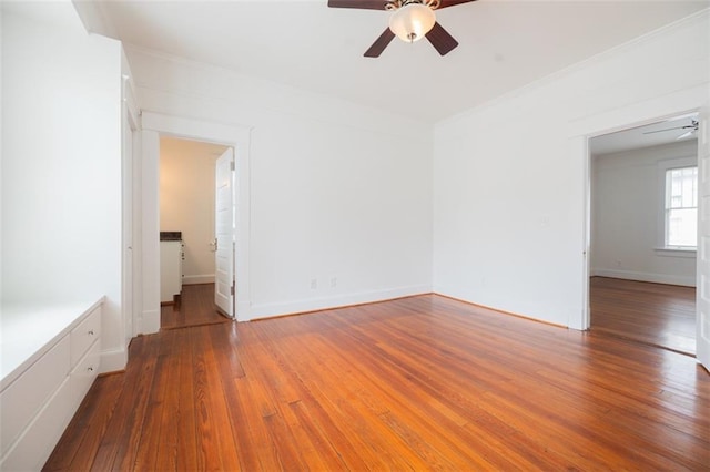 empty room with baseboards, wood-type flooring, ceiling fan, and crown molding