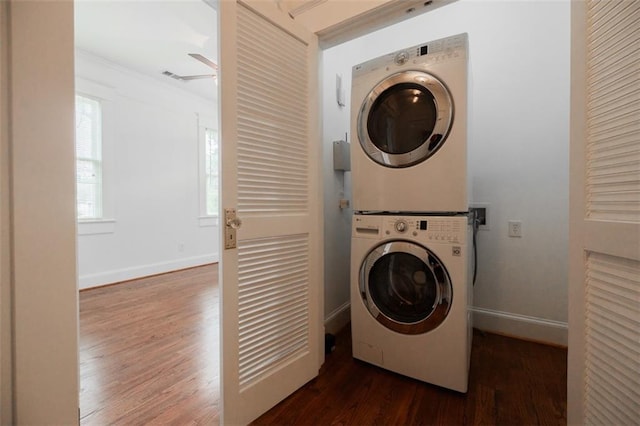 washroom featuring ceiling fan, baseboards, laundry area, stacked washer and clothes dryer, and wood finished floors