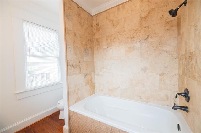 bathroom with crown molding, baseboards, toilet, shower / bathing tub combination, and wood finished floors